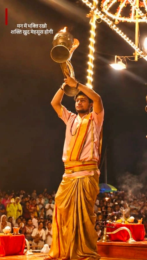 Priest performing Ganga Aarti with ceremonial lamp at night